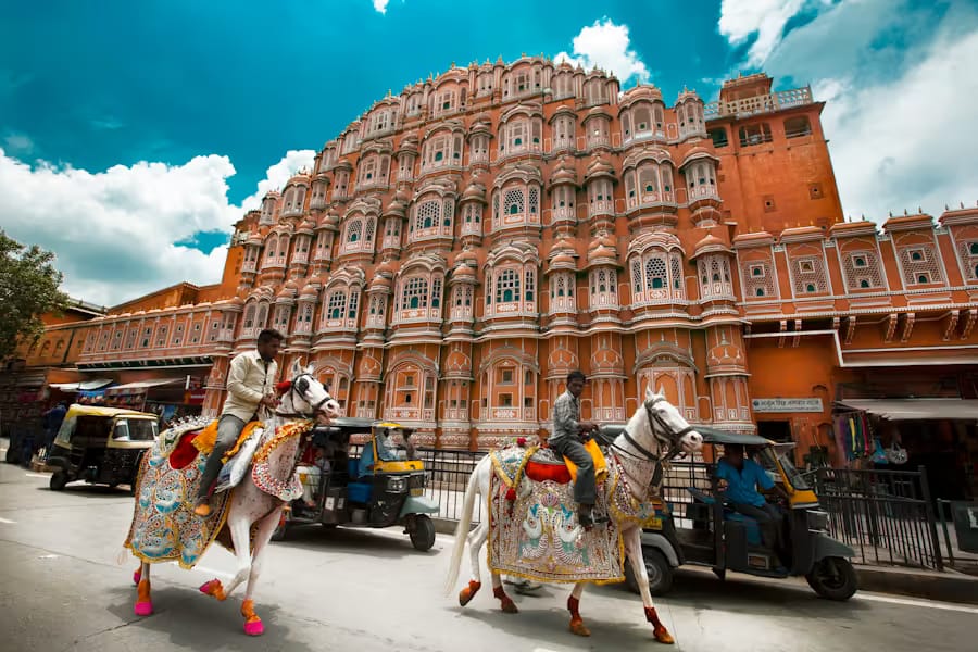 The pink facade of Hawa Mahal in Jaipur with street life passing below